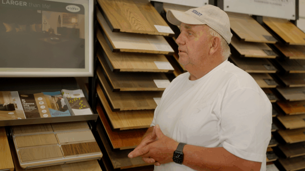 Explaining hardwood flooring options in front of the showroom sample wall